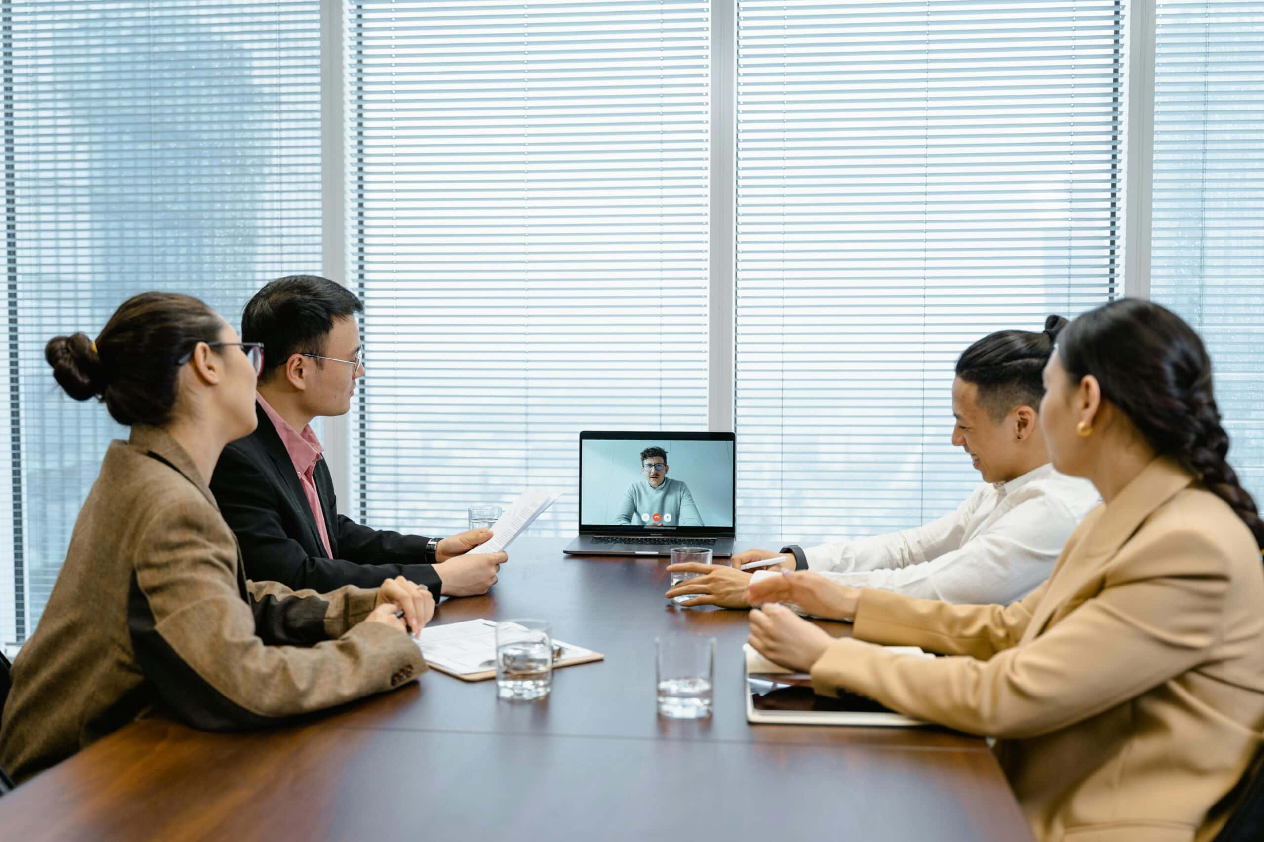 Mixed-use POA management team conducting a hybrid board meeting with members in person and one participant joining via video call.