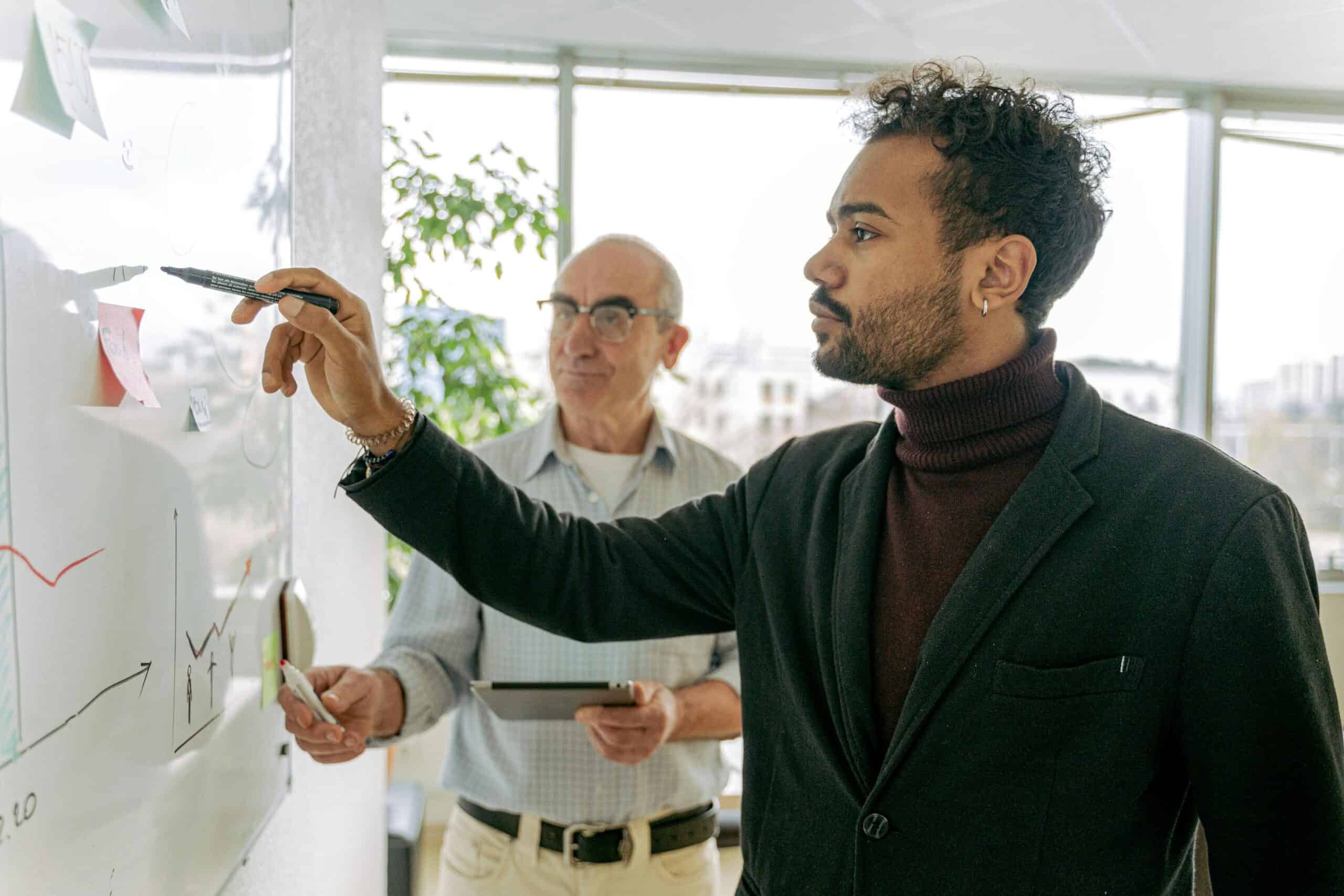 Two property management professionals discussing mixed-use POA strategies while analyzing charts on a whiteboard.