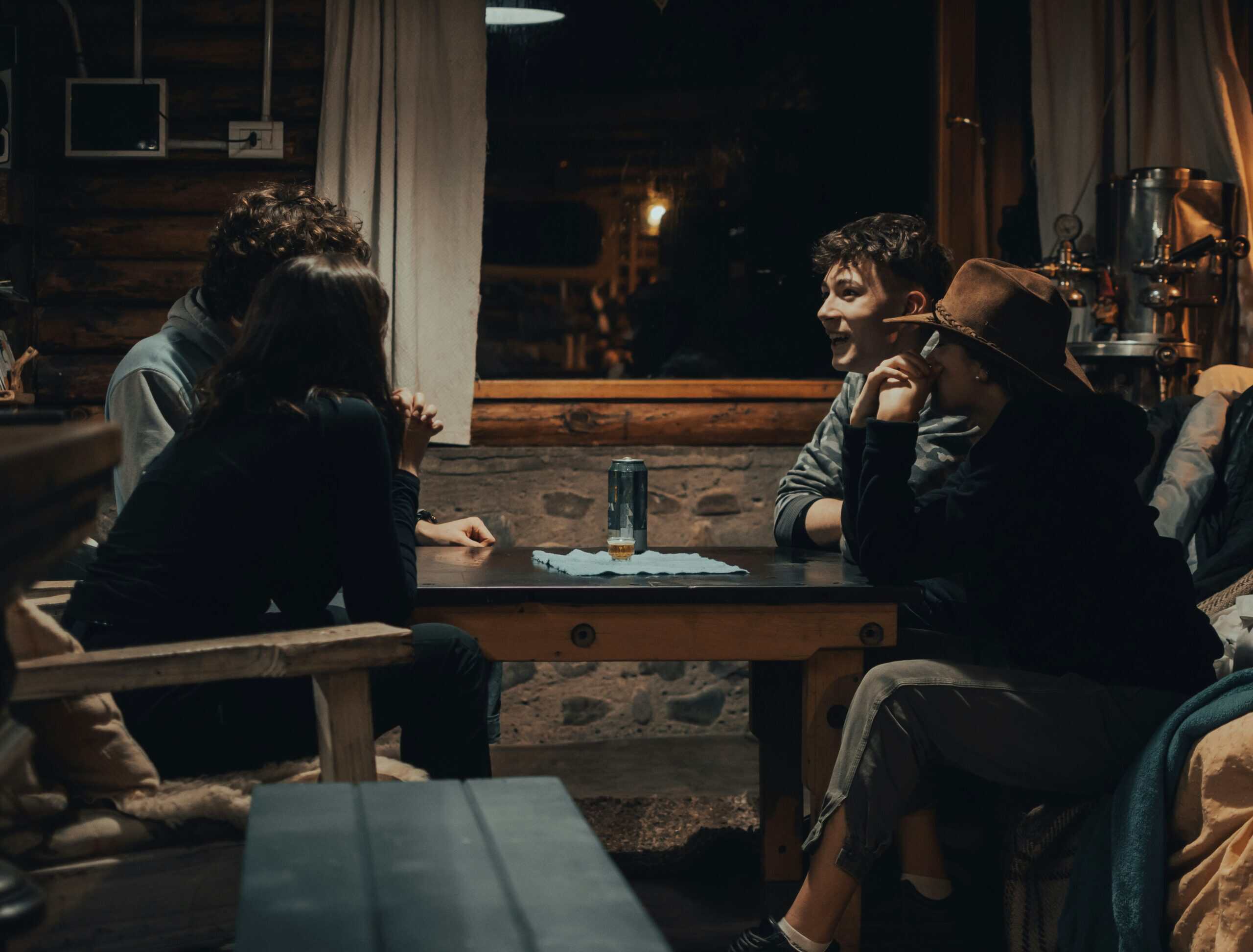 Group of friends sitting around a wooden table talking in a cozy cabin in Bedford County. Group of friends sitting around a wooden table talking in a cozy cabin in Bedford County.