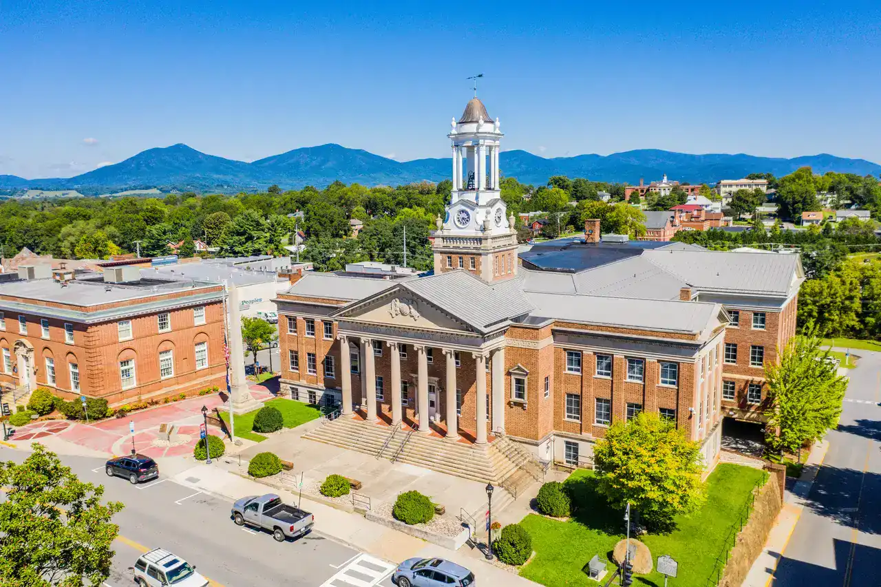 Aerial view of the Bedford County Courthouse with its clock tower, surrounded by historic brick buildings and mountain scenery. Aerial view of the Bedford County Courthouse with its clock tower, surrounded by historic brick buildings and mountain scenery.