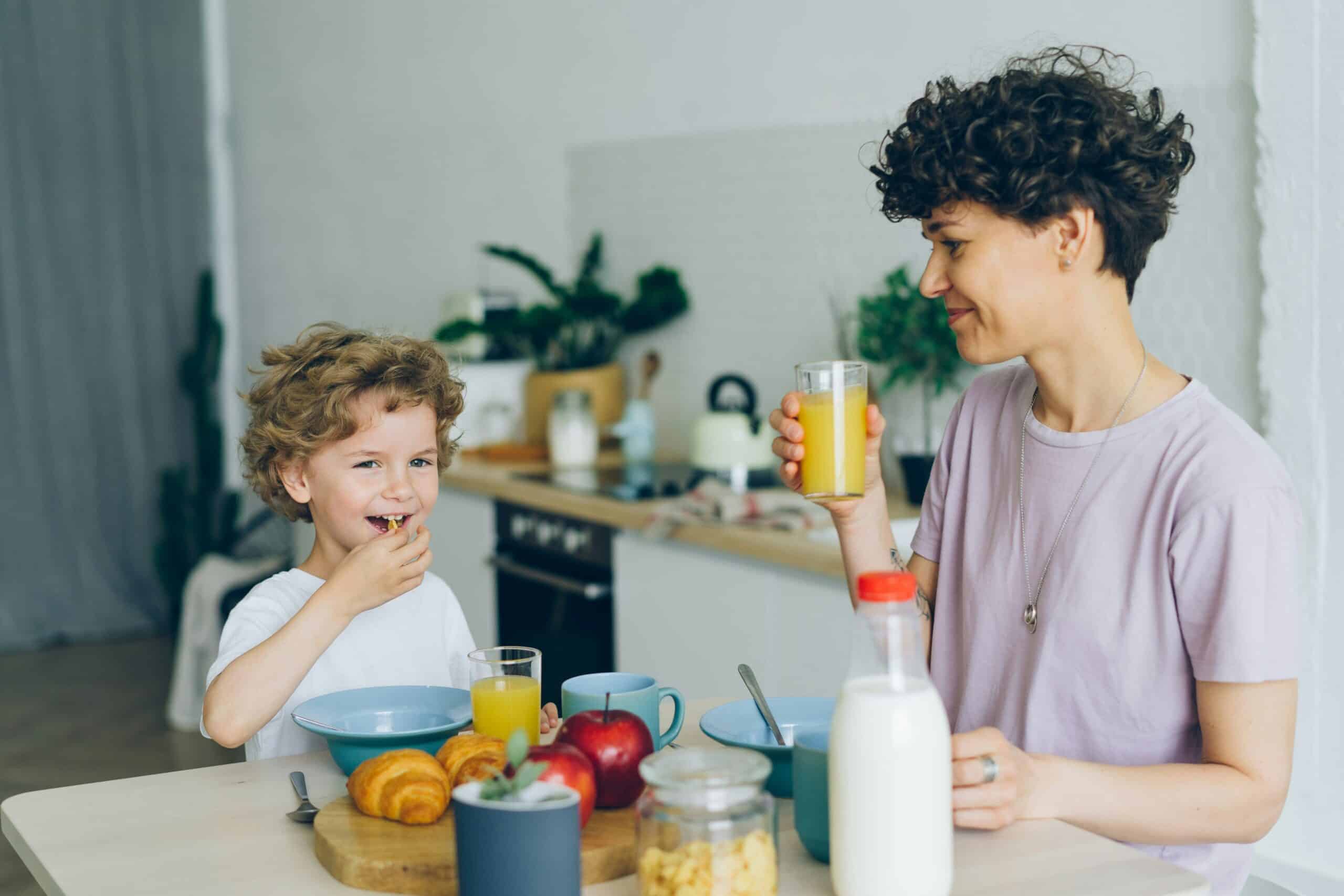 Parent and child enjoying breakfast together with orange juice and croissants in a bright kitchen in Stafford County.