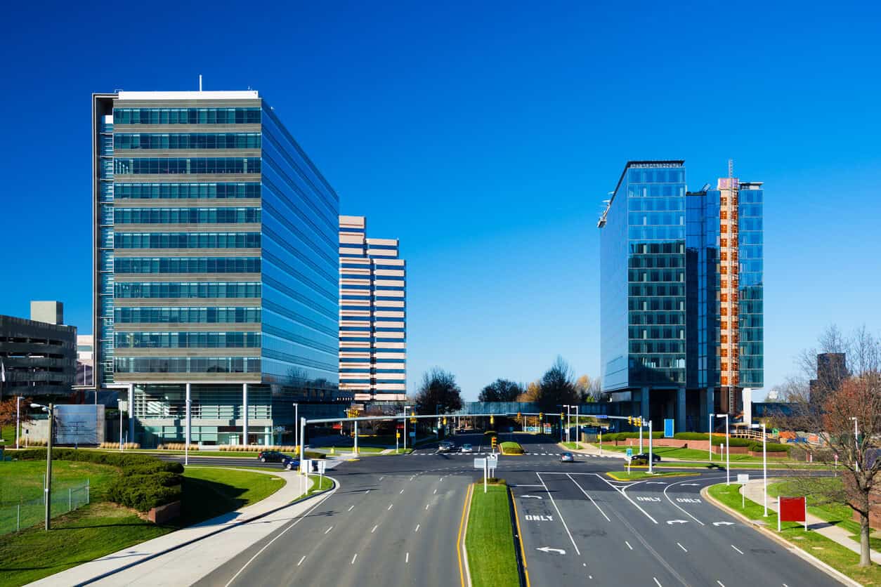 Wide boulevard and modern office towers in Fairfax County under a clear blue sky.