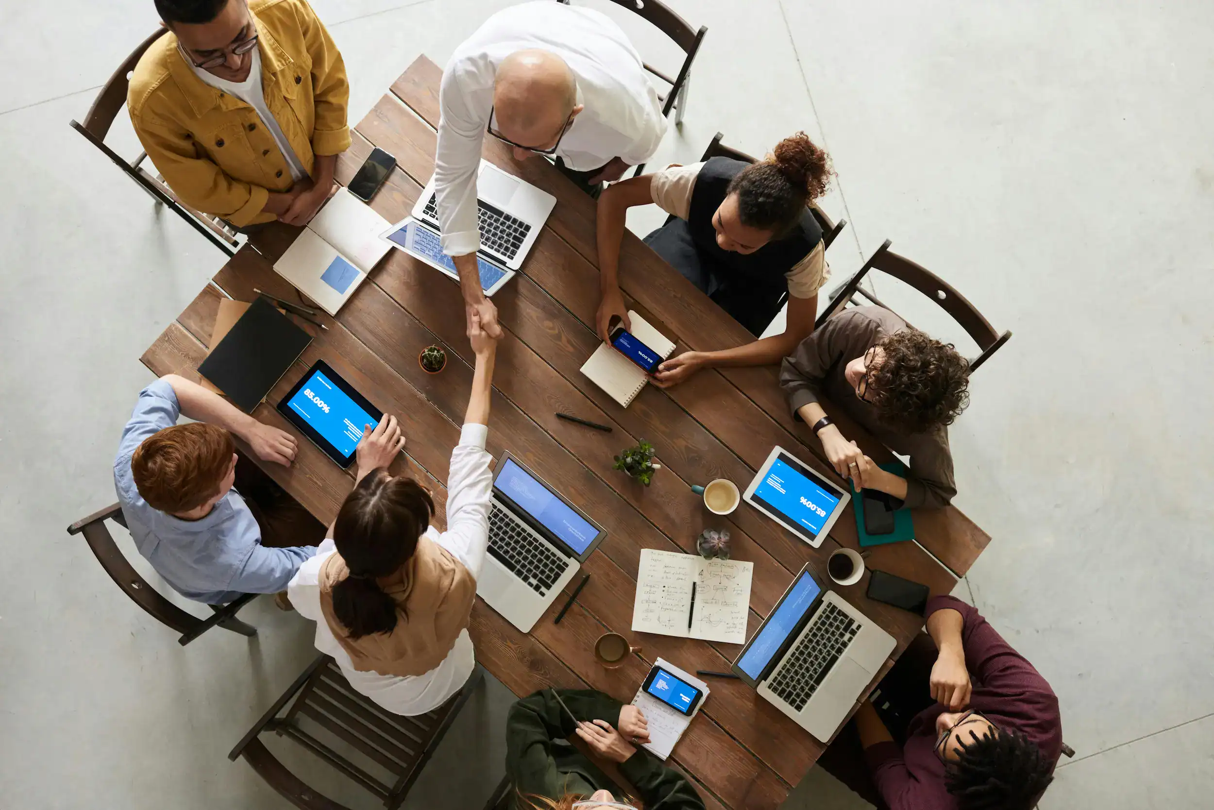 Group of professionals collaborating around a table with laptops and tablets during a meeting in Henrico County, Virginia.